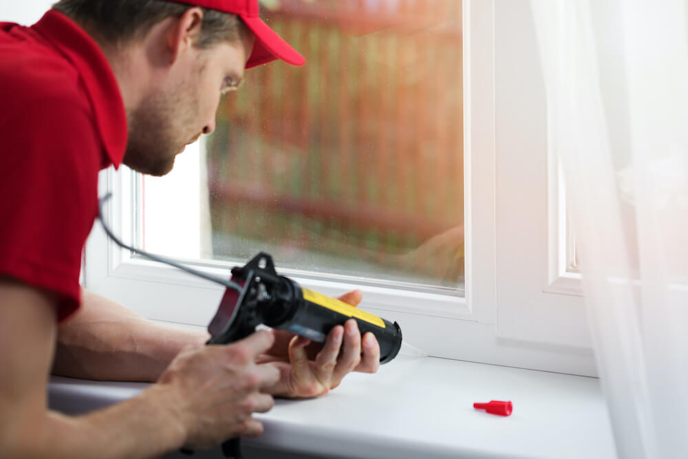 man sealing a white window