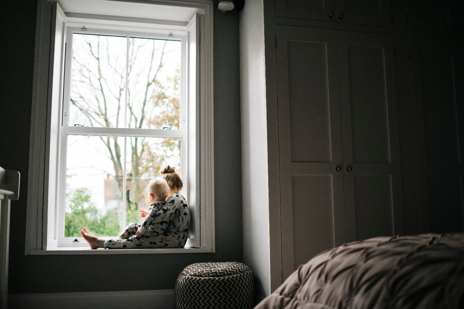 white sliding sash window in a bedroom with two siblings on a windowsill